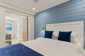 Une chambre à coucher avec un grand lit, un mur bleu et une tête de lit blanche.