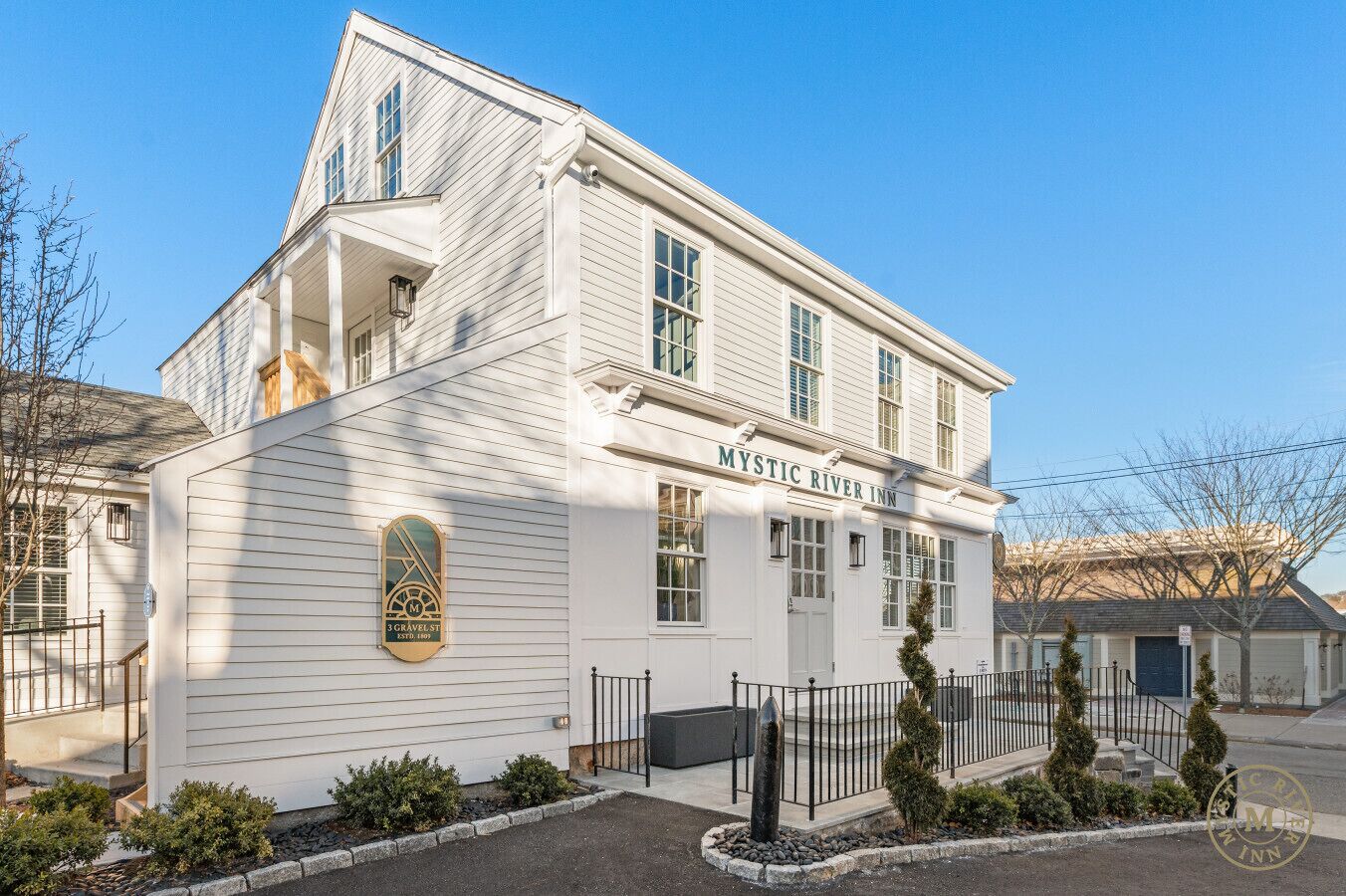En tvåvåningsbyggnad med en skylt högst upp där det står ”Mystic River Inn”.