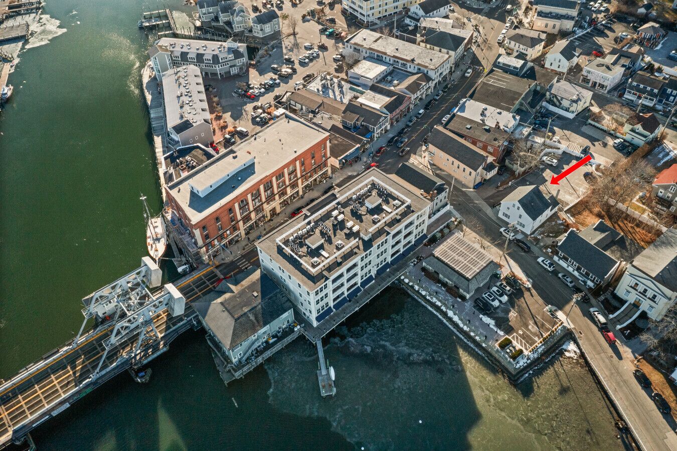 An aerial view of a waterfront area with buildings, a dock, and a bridge.