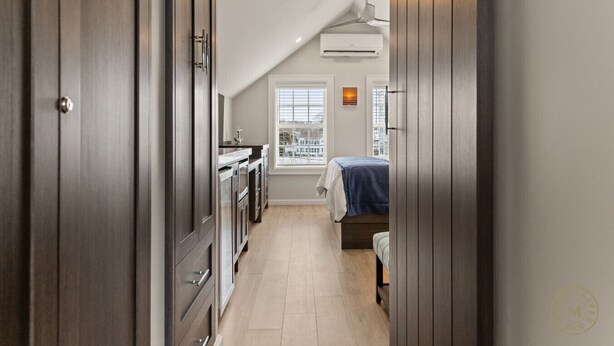 Un pasillo estrecho que conduce a un dormitorio con cama y ventana.