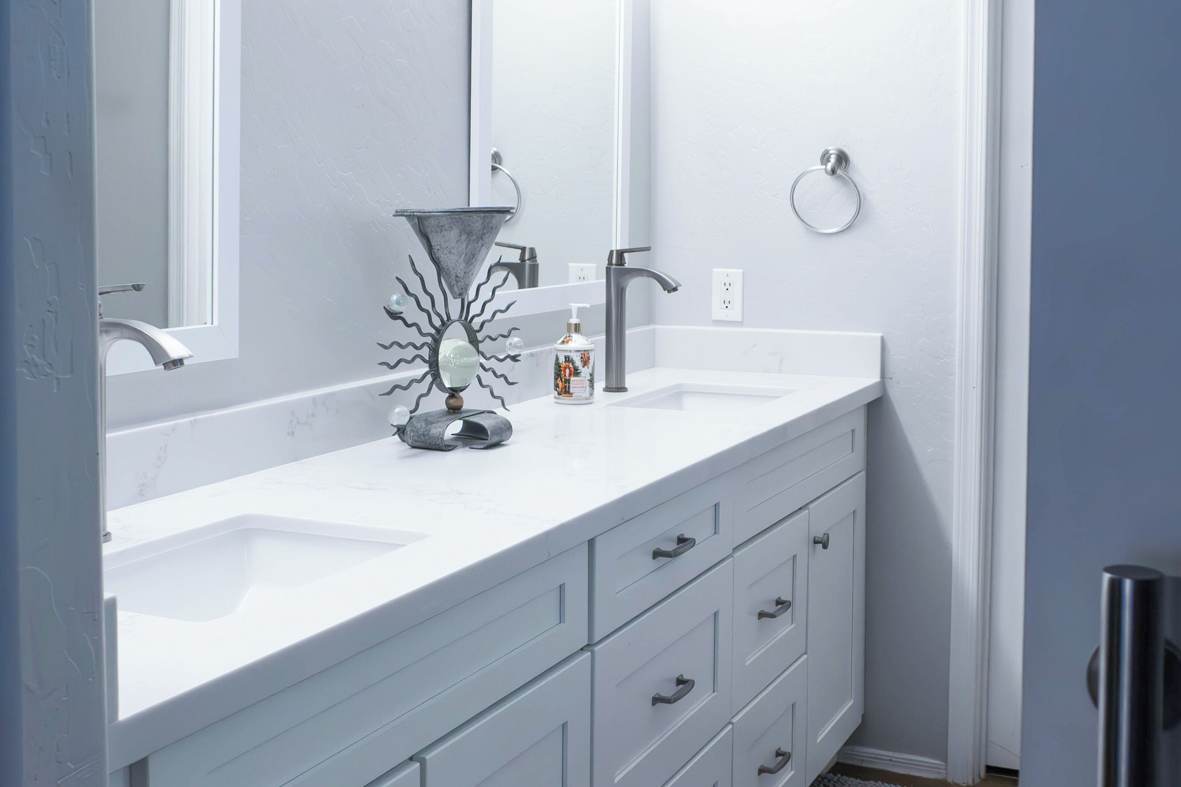 Un bagno moderno con un mobile lavabo bianco, uno specchio grande e un vaso decorativo originale.