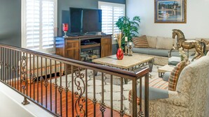 A living room with a television, sofa, and a decorative horse statue. - Group-Ready Glendale Oasis w/ Pool Grotto + Slide (Glendale)
