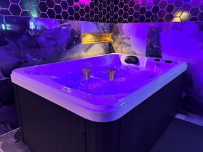 A hot tub with two glasses of champagne, surrounded by a hexagonal tile wall with a honeycomb pattern. - Cozy House Near Strasbourg (Achenheim)