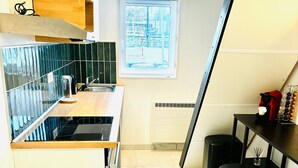 Cocina compacta con encimera de madera, estufa integrada, ventana con vistas y una pequeña barra con taburetes.
