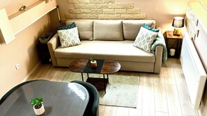 Una sala de estar acogedora con un sofá, una mesa de centro, un tapete pequeño, una lámpara y un ventanal con vistas.