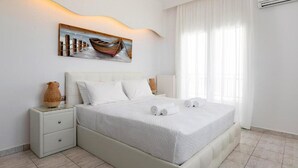 Ein modernes Schlafzimmer mit einem großen Bett, einem Nachttisch, einem Bild von einem Boot und einem Fenster mit Vorhängen.