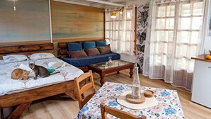 Ein gemütliches Zimmer mit einem Bett, einer Couch, einem Tisch mit einer Vase und Vorhängen.