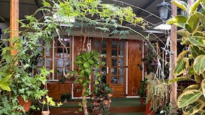 Ein Wintergarten mit verschiedenen Blumentöpfen, einem Holzstuhl und einer Treppe, die zu einer Glastür führt.