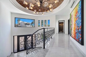 A modern interior with a staircase, a large abstract painting, and a framed photograph on the wall. - @ Marbella Lane – Coastal Elegance Villa w/ Pool (Cabo Bello)