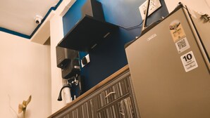 A kitchenette with a refrigerator, a stove, and a ceiling light fixture.
