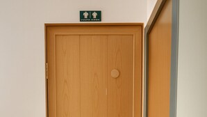 A wooden door with a sign above it indicating a men's restroom.