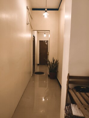 A hallway with a potted plant, a wooden bench, and a door at the end. - Veena Vihar (Full House) (Jodhpur)