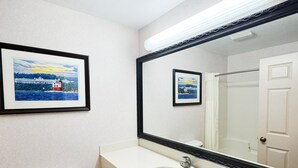 Un baño con un inodoro blanco, un lavabo y un espejo grande. Hay dos cuadros enmarcados en la pared.