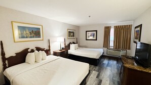 Habitación de hotel con dos camas, un televisor, un escritorio y una ventana con cortinas.