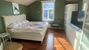 A bedroom with a bed, a window, a wardrobe, and a television.