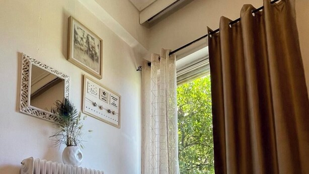 Een hotelkamer met een bed, twee handdoeken, een radiator, een spiegel en een raam met gordijnen.