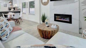 Een moderne woonkamer met een bank, salontafel en een wandgemonteerde flatscreen-televisie.
