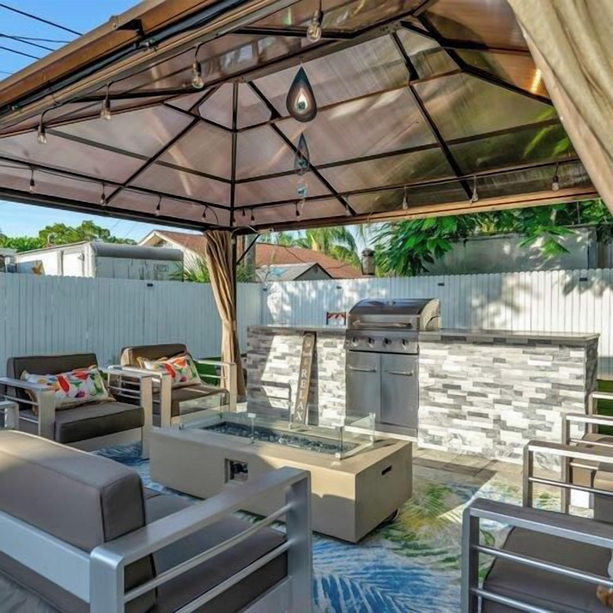 An outdoor patio with a grill, seating area, and a glass enclosure.
