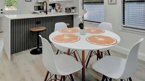 Een moderne keuken met witte kastjes, een centraal eiland en hanglampen.