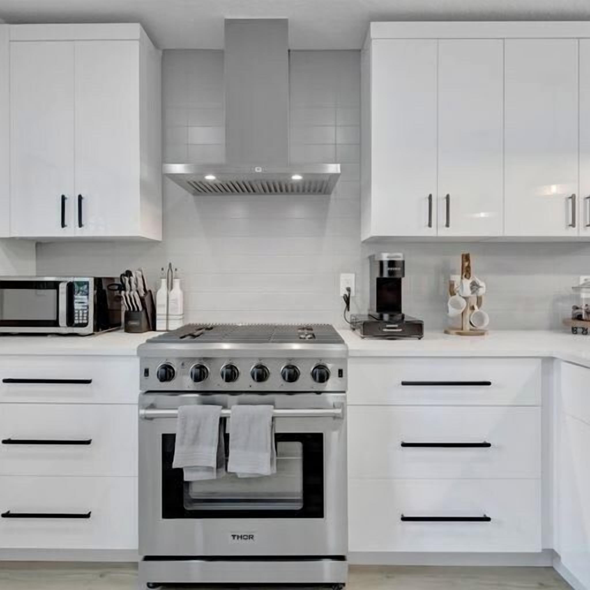 A modern kitchen with white cabinetry, a stainless steel stove, and a microwave.
