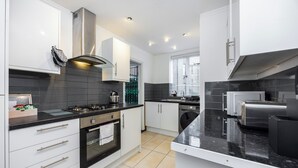 A modern kitchen with white cabinetry, a gas stove, a built-in oven, and a stainless steel range hood. - A Nice Apartment in Central London, Great For Sightseeing (London)
