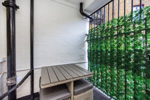 A corner with a table and a wicker bench, a white brick wall, and a green plant wall. - A Nice Apartment in Central London, Great For Sightseeing (London)