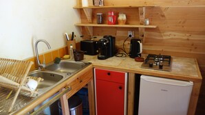 Eine kleine Küche mit Spüle, einem roten Schrank, einem weißen Kühlschrank und einer Holzarbeitsplatte.