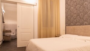 Habitació d'hotel amb llit, bany amb banyera i vàter, i paret amb un disseny decoratiu.