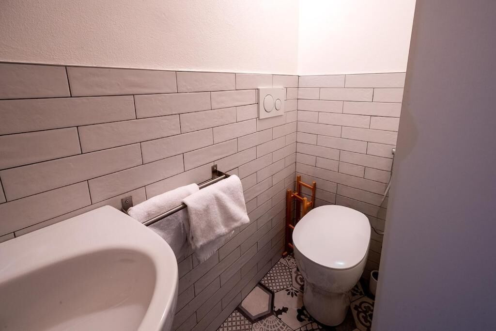 A bathroom with a white bathtub, a toilet, and a towel rack.