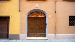 Una porta doble de fusta amb un arc decoratiu a la part superior, flanquejada per dues finestres amb reixes metàl·liques.