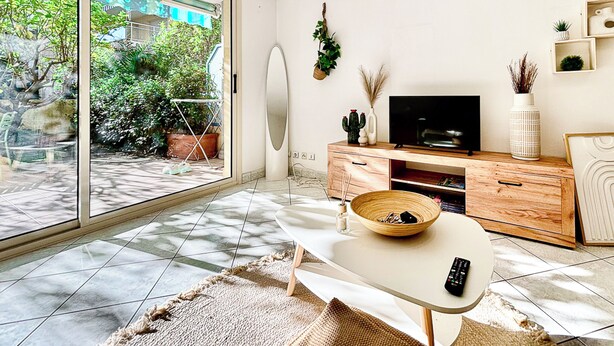 Een moderne woonkamer met een televisie, een houten kast en een eettafel.