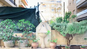 Een binnenplaats met plantenpotten, een stenen fontein en een gebouw op de achtergrond.