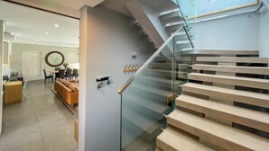 A modern interior with a glass staircase, a dining area, and a map on the wall.