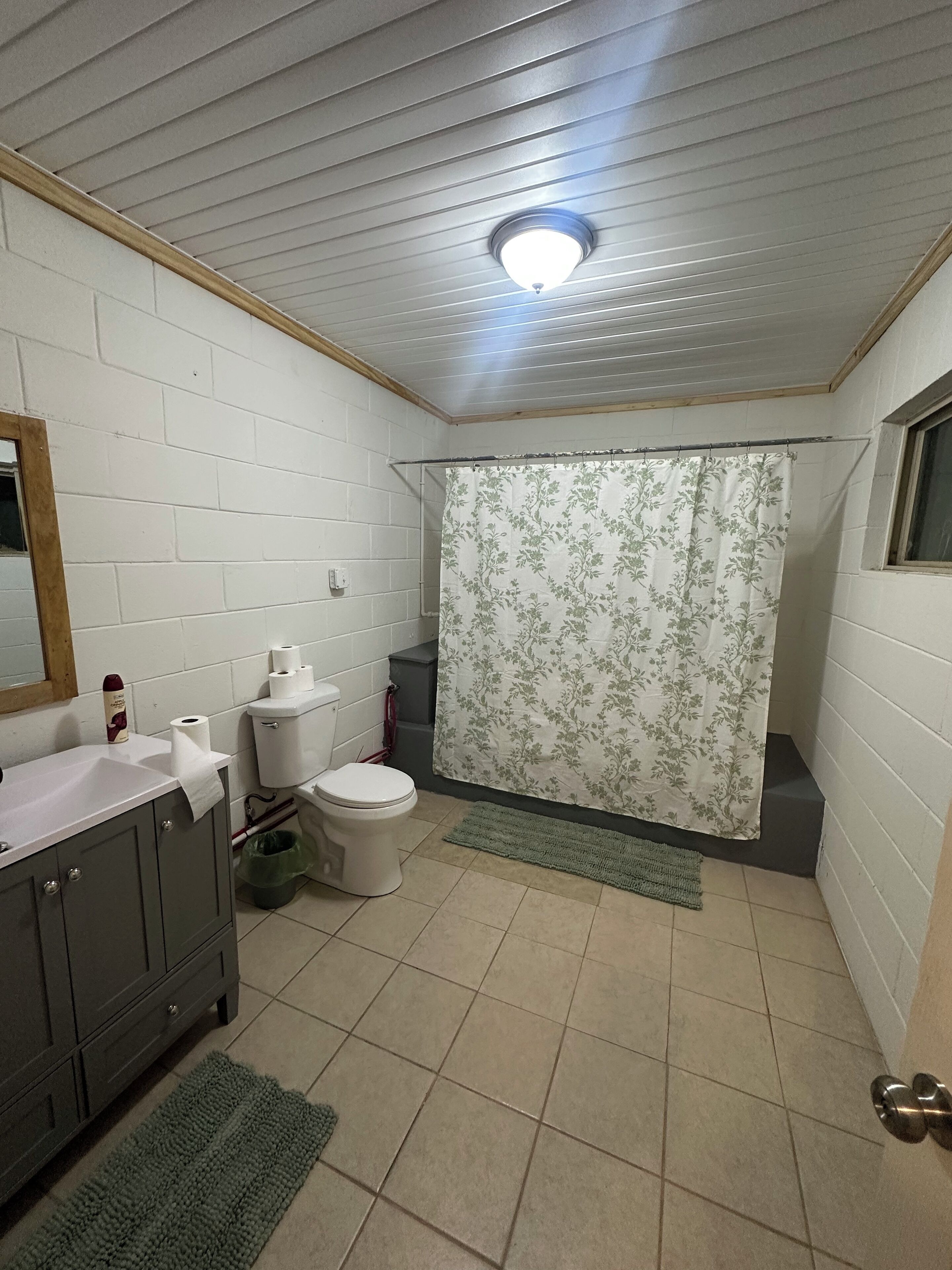 A small, compact bathroom with a toilet, sink, and shower curtain.