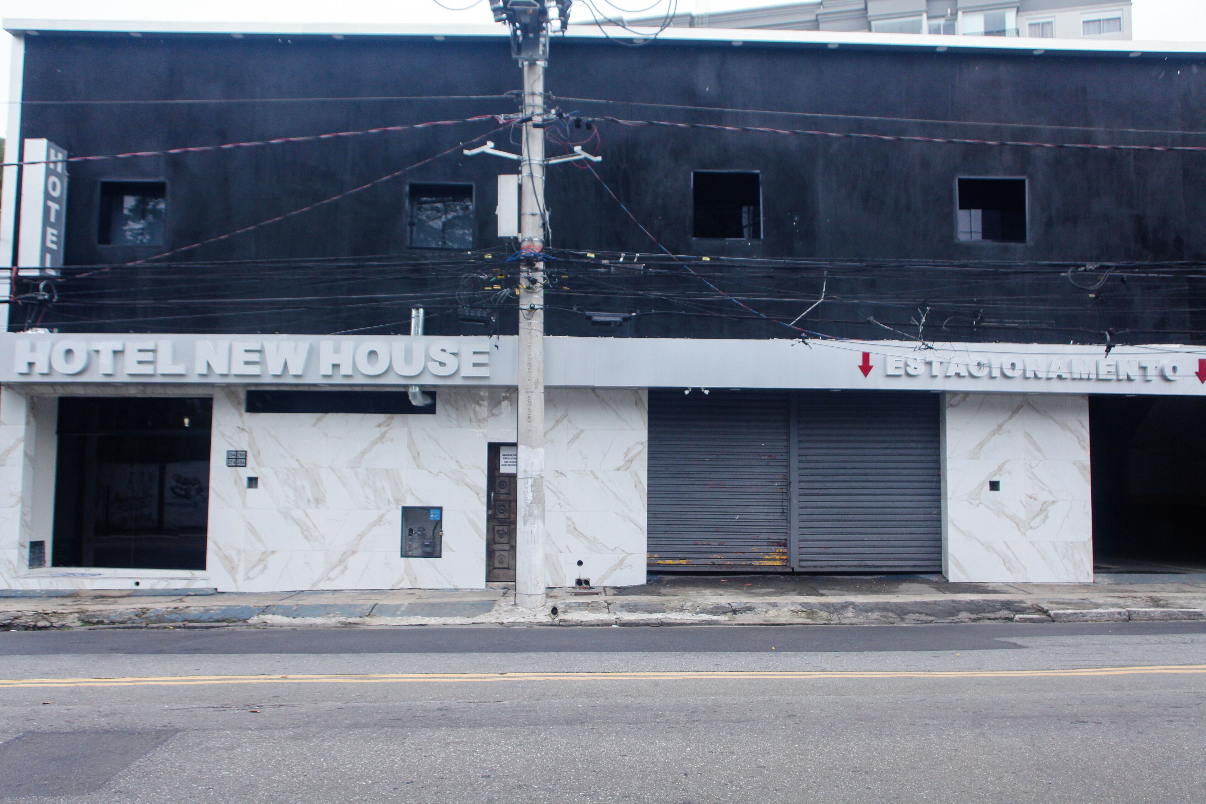 A building with a sign that reads "HOTEL NEW HOUSE" and another sign that says "ESTACIONAMIENTO".