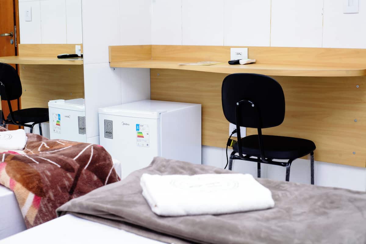 Una camera d'albergo con un letto, una scrivania, una sedia e una lavatrice.