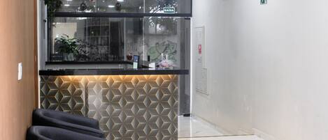 A reception area with a modern design, including a geometric patterned wall, a reception desk, and a seating area with chairs.