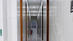 Corredor moderno e elegante, com pisos de mármore branco e portas de madeira, que dá acesso a uma escadaria.