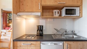 Una cocina con armarios de madera, microondas, cafetera, lavaplatos y lavavajillas.