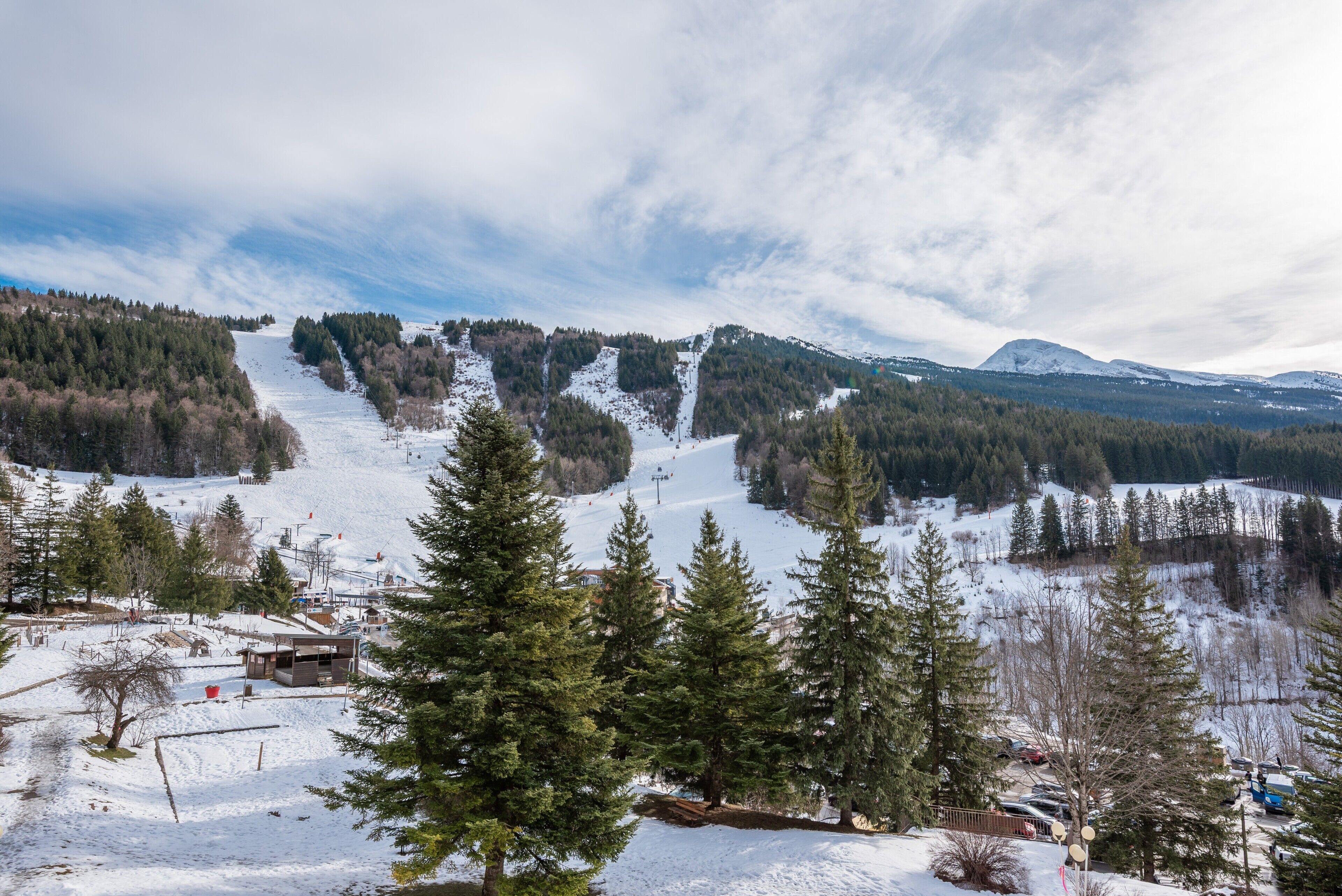 Paisagem montanhosa coberta de neve com estação de esqui, incluindo teleféricos e pistas.