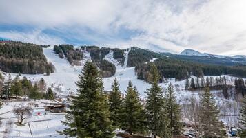 Paisagem montanhosa coberta de neve com estação de esqui, incluindo teleféricos e pistas.