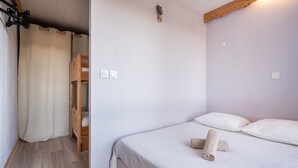 Un dormitorio con una cama, un armario de madera, una cortina y una lámpara en el techo.