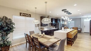 Una cocina moderna con armarios oscuros, una isla central e iluminación colgante.