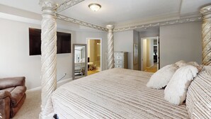 Un dormitorio con cama con dosel, un espejo grande y un armario.