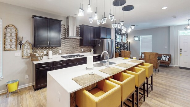 Una cocina moderna con una isla central, muebles oscuros e iluminación colgante.