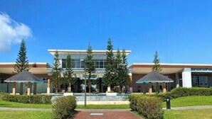 A modern building with a central atrium, surrounded by trees and a small fountain.