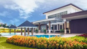 A modern two-story house with a swimming pool, covered patio, and landscaped garden.
