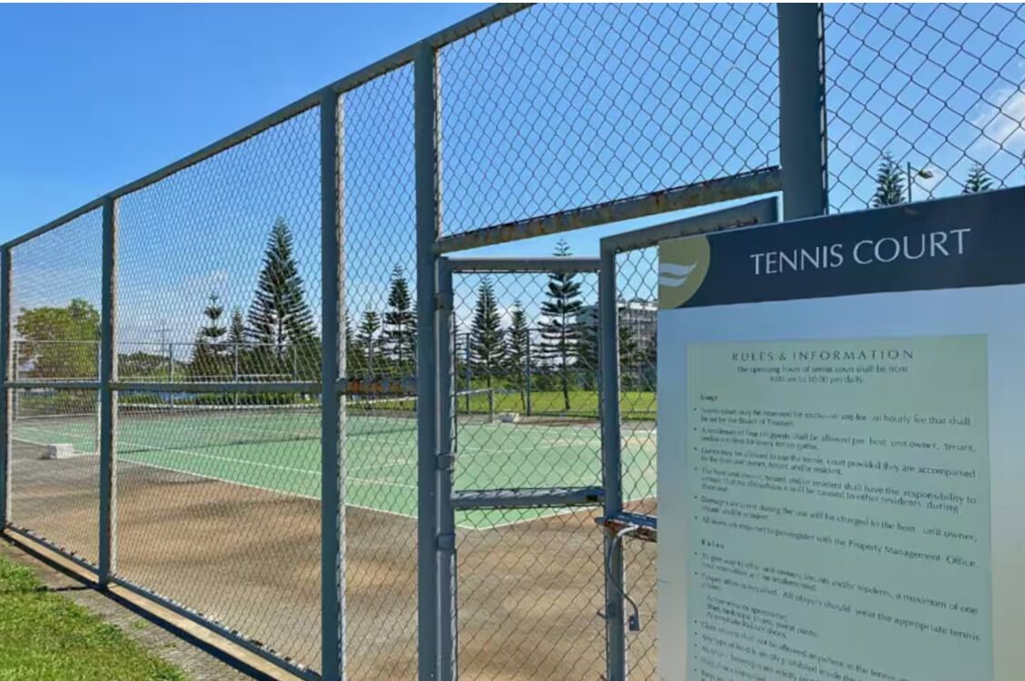 A tennis court with a sign indicating rules and information.