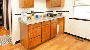 Una cocina con gabinetes de madera, un lavamanos de acero inoxidable y un ventanal.