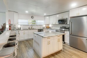 A modern kitchen with white cabinetry, stainless steel appliances, and a marble countertop.